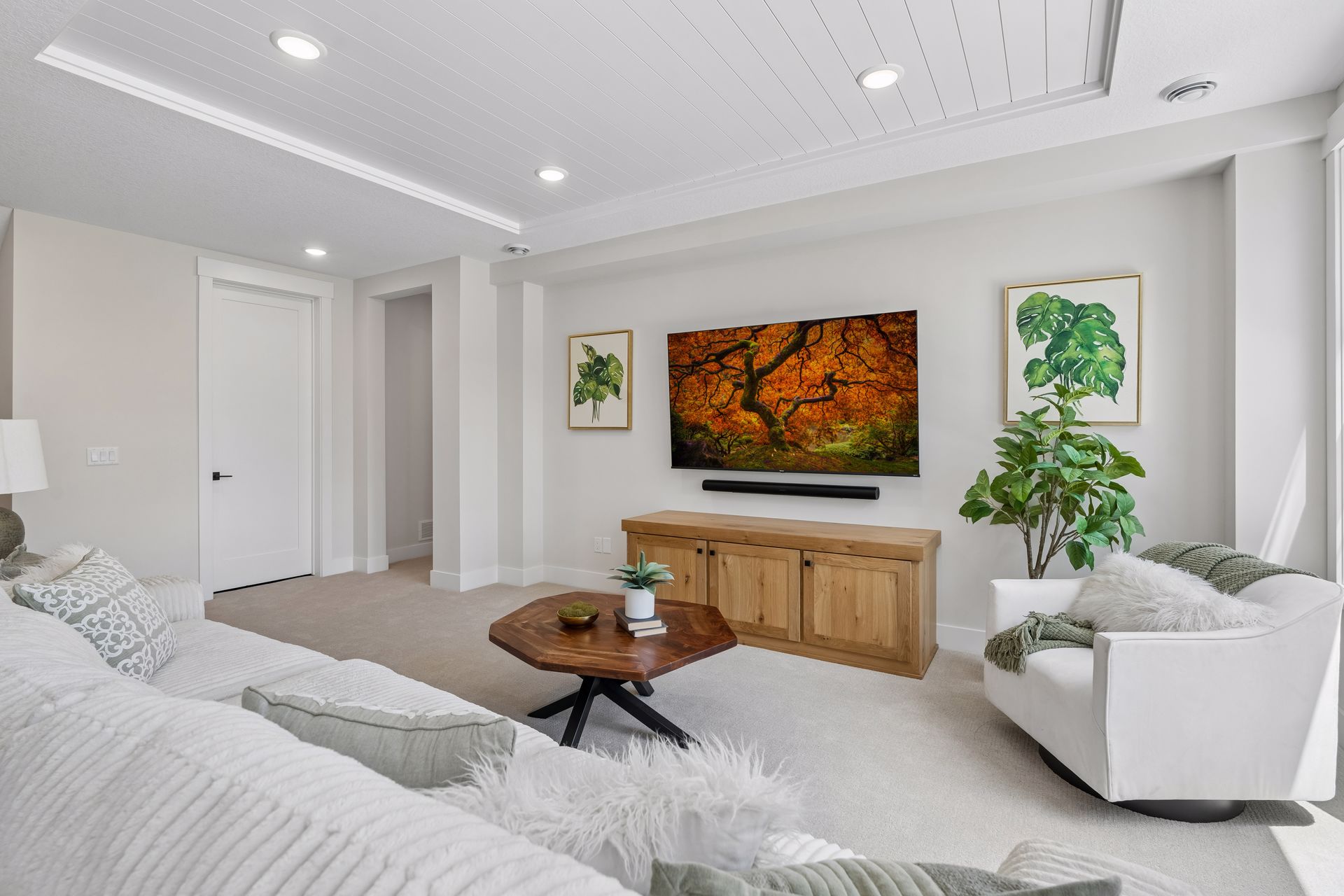 Lower level recreation room with media wall, seating area and wood cabinet